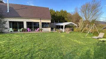 Une maison dotée d’un patio couvert, d’un espace salon extérieur et d’une balançoire.