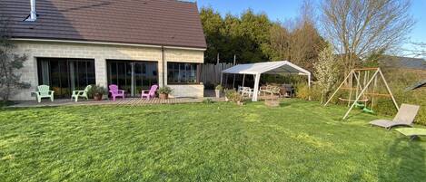 Une maison dotée d’un patio couvert, d’un espace salon extérieur et d’une balançoire.