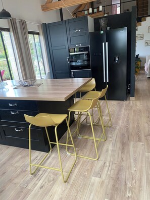 Eine moderne Küche mit einer Holzinsel, schwarzen Schränken, einem schwarzen Kühlschrank und gelben Barhocker.