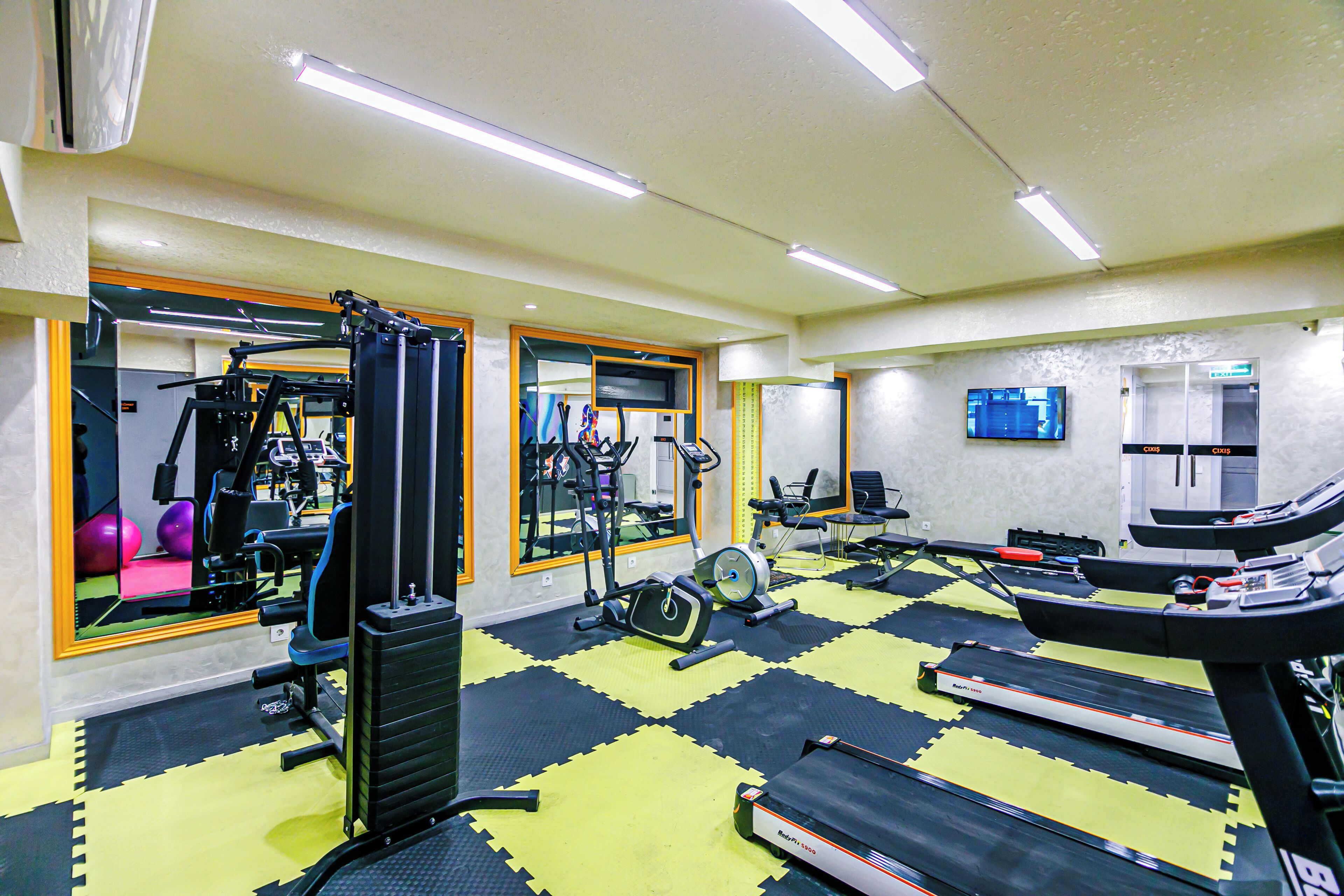 Un gimnasio con equipo de ejercicio, una cinta de correr y un espejo grande.