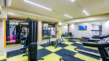 Un gimnasio con equipo de ejercicio, una cinta de correr y un espejo grande.