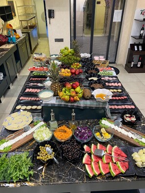 A buffet spread with various fruits, vegetables, and meats. - Essam Deluxe Hotel (Baku)