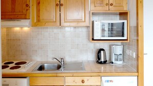 Una cucina con mobili in legno, un forno a microonde, un bollitore e una macchina per il caffè.