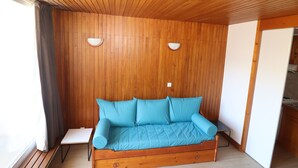 Una stanza con rivestimenti in legno, un divano blu, due luci a parete e un tavolino.
