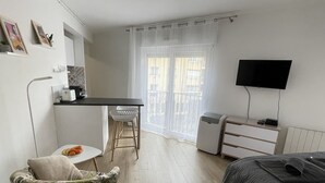 Pieni hotellihuone, jossa on sänky, pieni työpöytä tuolilla, televisio ja patteri.