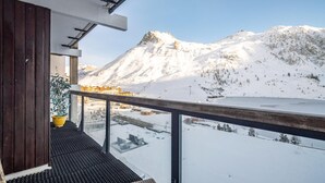 Un balcon offrant une vue sur des montagnes enneigées et une station de ski située en contrebas.
