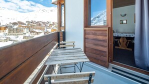 A balcony with wooden benches, a wooden door, and a view of a snowy mountain town. - Cozy ski-in/ski-out apartment with balcony in Tignes (Tignes)