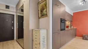 A modern kitchen with a red accent wall, a large oven, and a built-in microwave. - Sina Apartment (Voluntari)