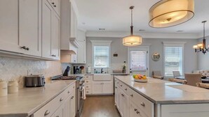A modern kitchen with white cabinetry, a central island, and pendant lighting. - Villa De Luxe Near Forsyth Park w/Private Hot Tub (Savannah)