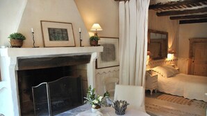 A cozy room with a fireplace, a bed, and a seating area with a table. - Daudet Romantic two-person apartment in Provence (St Remy de Provence Quartier de Paluds)