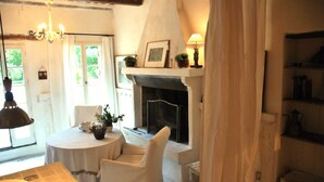A cozy room with a fireplace, a table with chairs, and a hanging lamp. - Daudet Romantic two-person apartment in Provence (St Remy de Provence Quartier de Paluds)