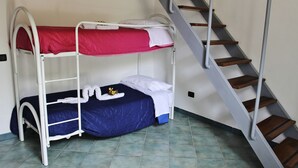 Ein Schlafsaalzimmer mit Etagenbetten, einer Treppe und Fliesenboden.