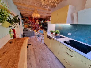 Une cuisine moderne avec des meubles en bois, une cuisinière encastrée et un coin repas comprenant un canapé et une table.