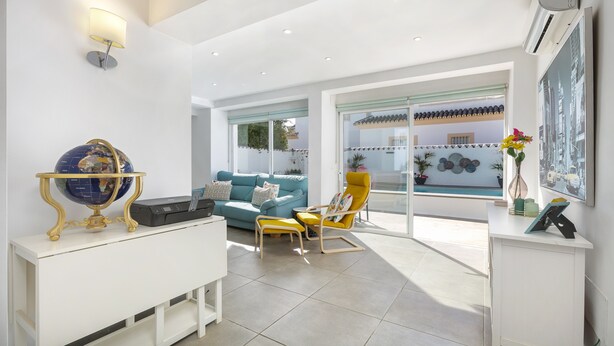 A modern living room with a sofa, a yellow armchair, a globe on a white console table, and a large window with a view of a building. - Spanish villa with private pool , only 5 minutes from the beach! (San Pedro de Alcantara)