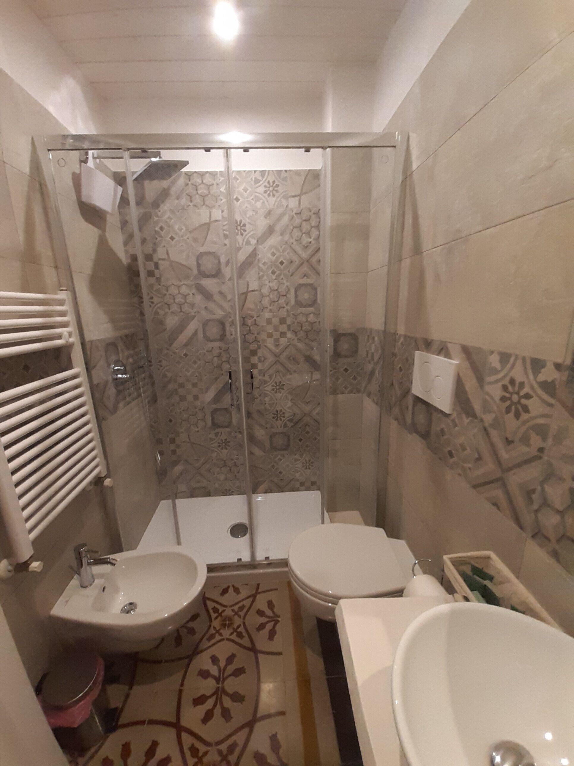 A bathroom with a shower, two toilets, a sink, and a bathtub.
