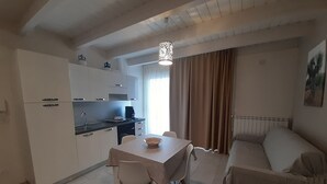 Ein kompakter Wohnbereich mit Küchenzeile, Essplatz und einer Couch.