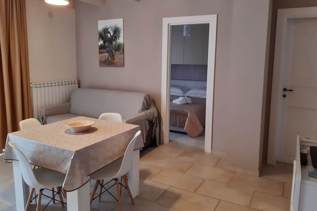 Un espacio habitable compacto con zona de comedor, sofá y cama.