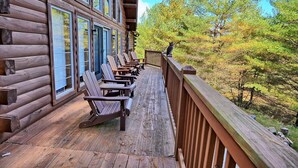 Eine Blockhütte mit einer Holzterrasse und Adirondack-Stühlen.