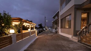 A narrow street with a wooden pergola and a white building with large windows and a staircase. - Sevasti Seaview Suite (Rhodes)
