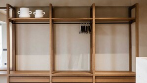 A wooden shelving unit with two white ceramic cups on the top shelf and a set of black keys hanging on the middle shelf. - Sevasti Seaview Suite (Rhodes)