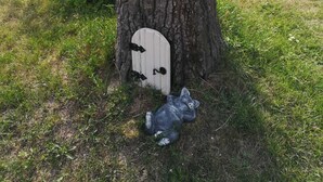 Une cabane dans les arbres avec un toit triangulaire, une petite fenêtre et une porte.