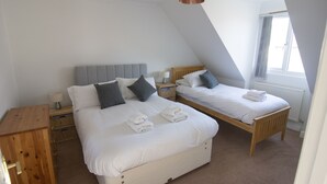 A bedroom with two beds, a wooden nightstand, a lamp, and a wooden cabinet. - Bilbo's Cottage, Sheringham (Sheringham)