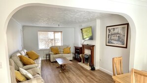 A living room with a sofa, armchair, coffee table, fireplace, and a painting on the wall. - Bilbo's Cottage, Sheringham (Sheringham)