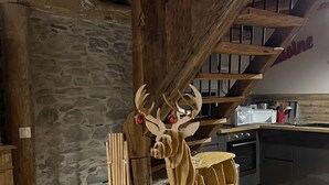 Una cocina rústica con una escultura de ciervo de madera, paredes de piedra y suelo de baldosas.