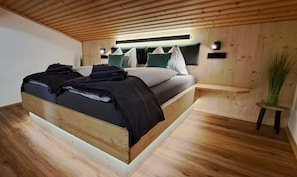 A wooden bed with a headboard, a bedside table, and a wall-mounted light fixture.
