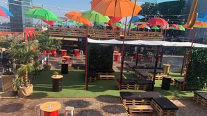 An outdoor seating area with tables and chairs, surrounded by potted plants and umbrellas. - Room-quiet Single Bedroom in the Centre (Zagreb)