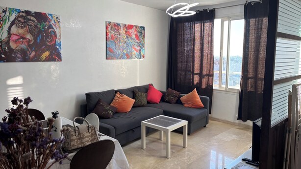 Una sala de estar moderna con un sofá gris, una mesa de centro y obras de arte en las paredes.
