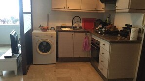 Cocina compacta con lavadora, lavaplatos y una pequeña encimera con diversos objetos.