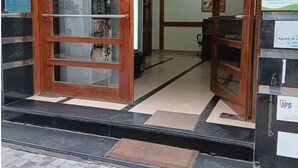 Entrada de un hotel con puerta de madera, suelo de baldosas y mostrador de recepción.