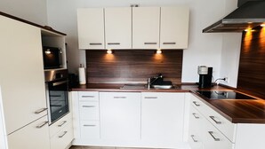 Eine moderne Küche mit weißen Schränken, einer Holz Arbeitsplatte und einem eingebauten Backofen.