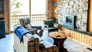A cozy living room with a stone wall, a fireplace, and a large window.