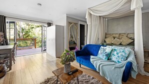 A spacious room with a large bed, a wooden coffee table, and a view of the outdoors through a sliding glass door.