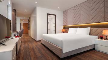 Een moderne hotelkamer met een groot bed, een bureau met stoel, een douche en een houten vloer.