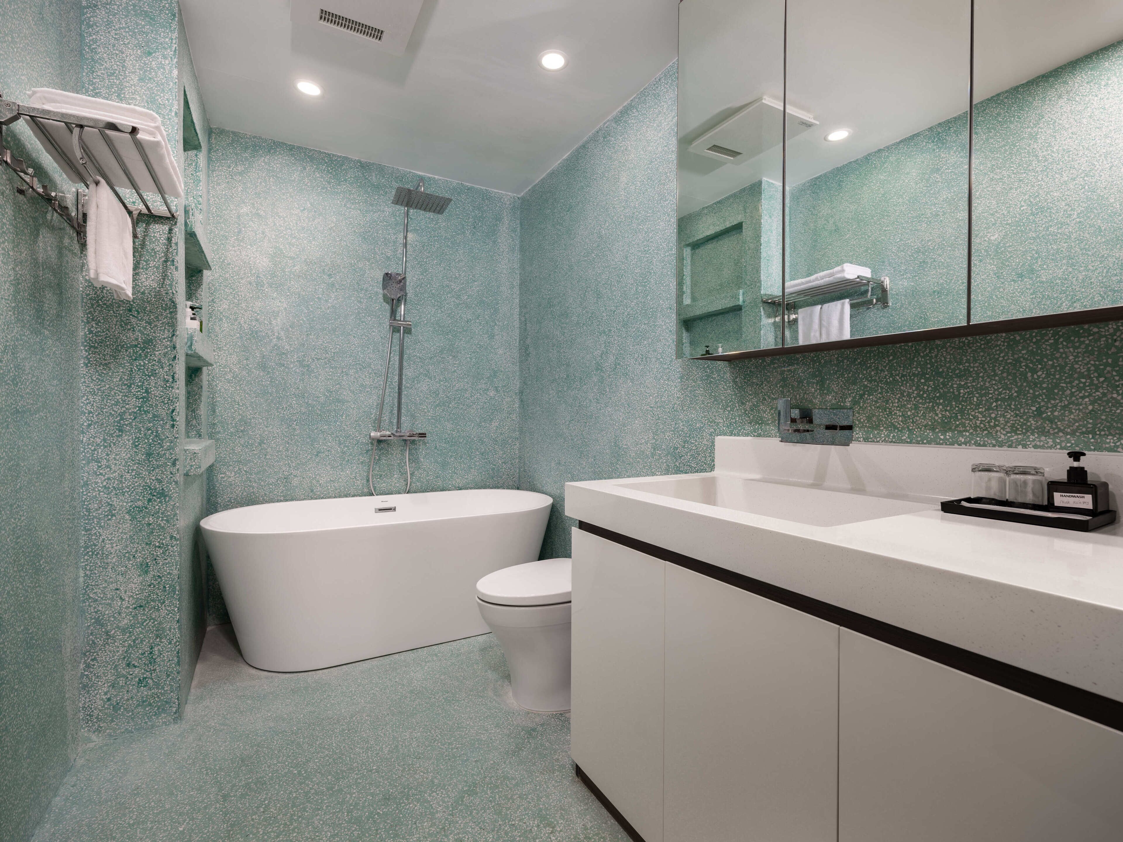 A modern bathroom with a freestanding bathtub, a toilet, and a sink with a mirror above.