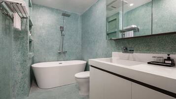 A modern bathroom with a freestanding bathtub, a toilet, and a sink with a mirror above.