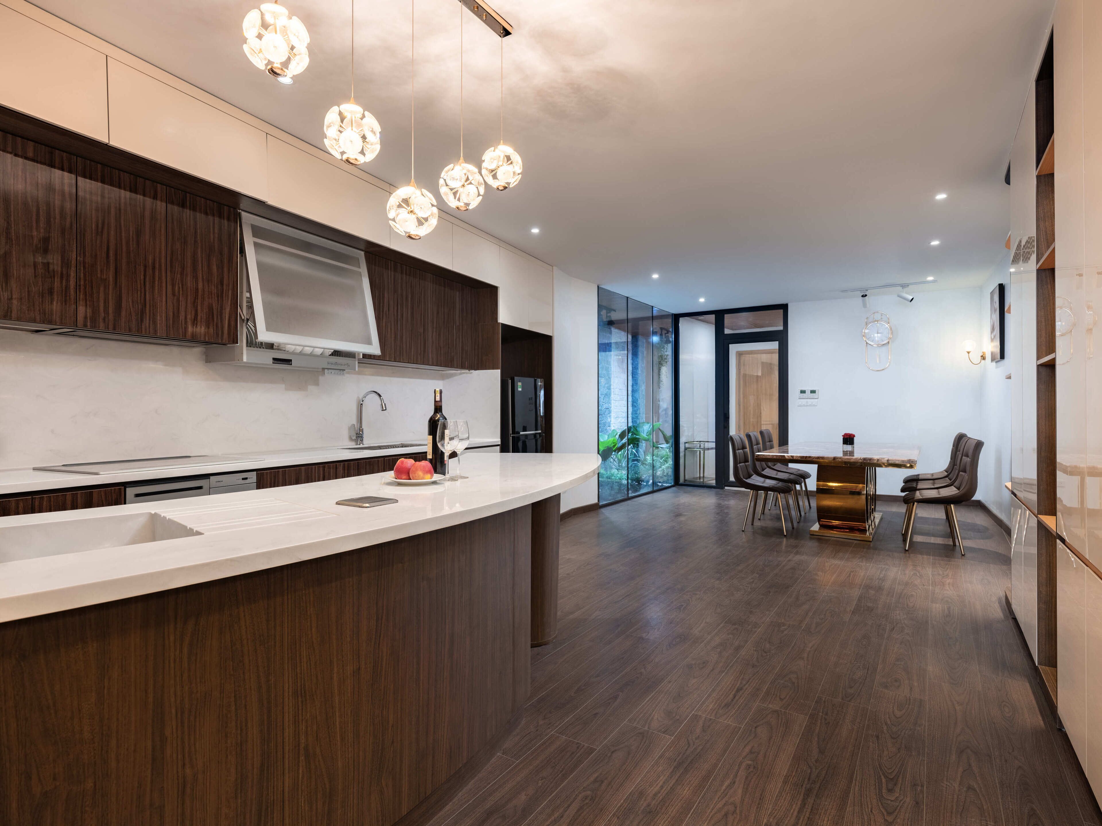 A modern kitchen with a central island, wooden cabinets, and pendant lighting.