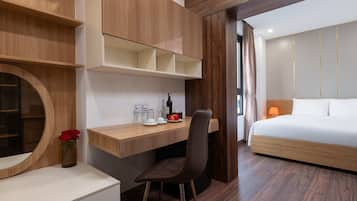 A modern hotel room with a wooden desk, a chair, a bed, and a wardrobe.