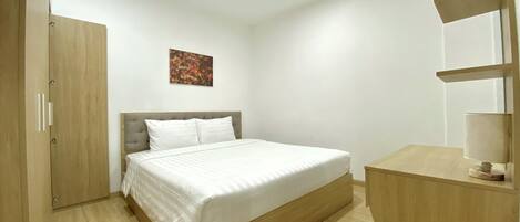 Una camera da letto con un letto, un armadio in legno, una scrivania con una lampada e un quadro appeso al muro.