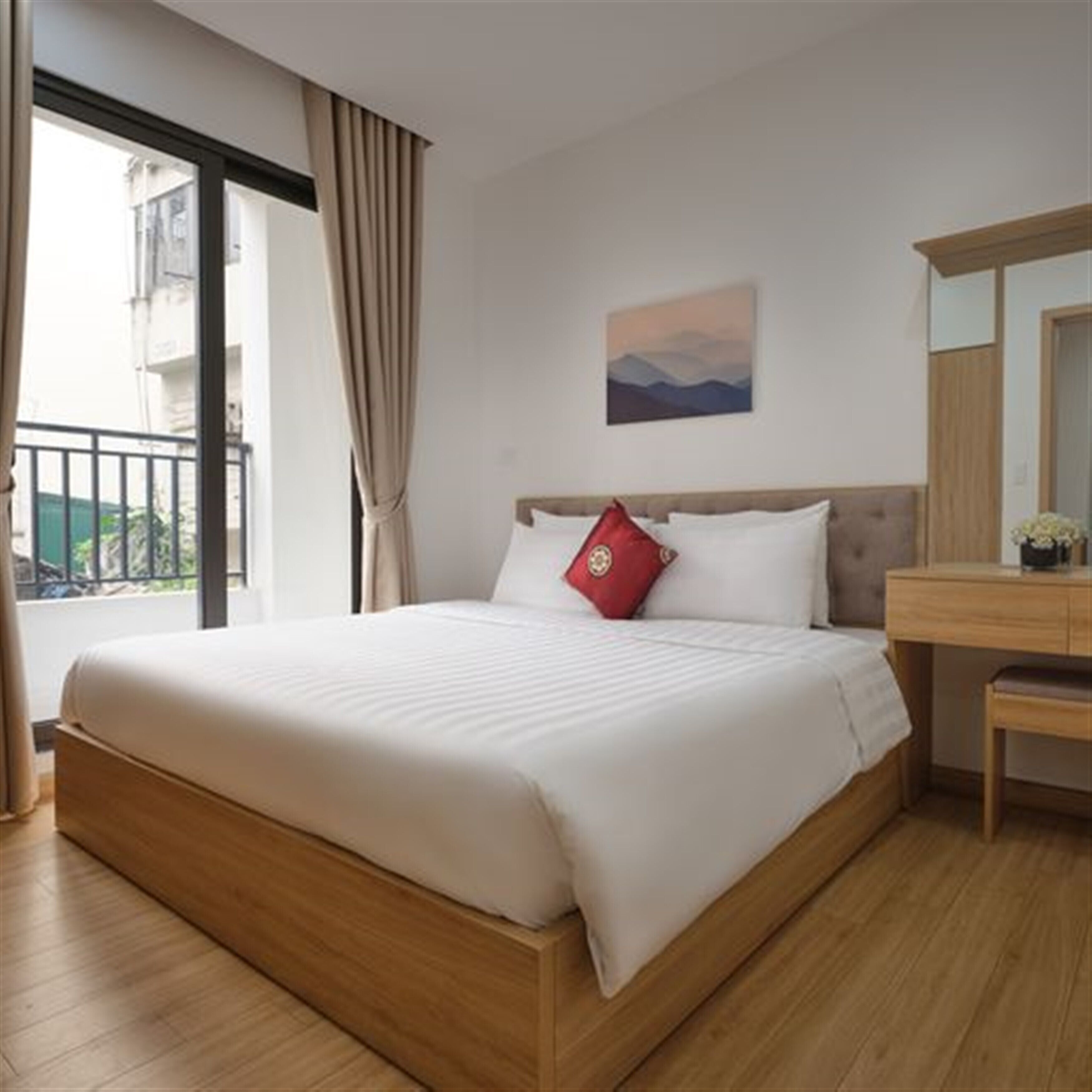 Una habitación de hotel con una cama grande, un cabecero de madera, una mesita de noche, un espejo y una ventana con cortinas.