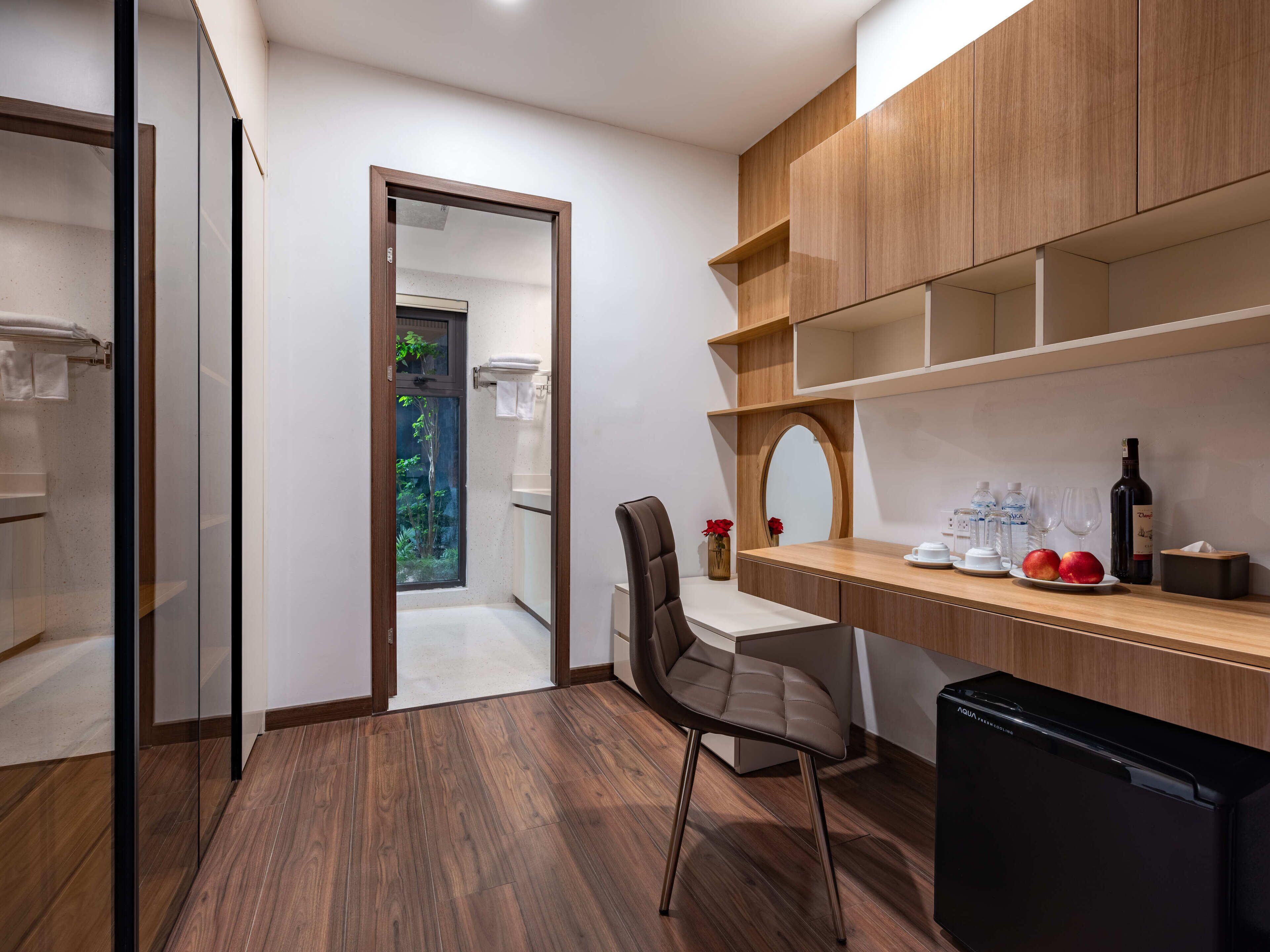 A modern kitchen with wooden cabinets, a built-in dishwasher, and a small dining area with a chair.