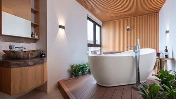 A modern bathroom with a freestanding bathtub, wooden paneling, and a large window.