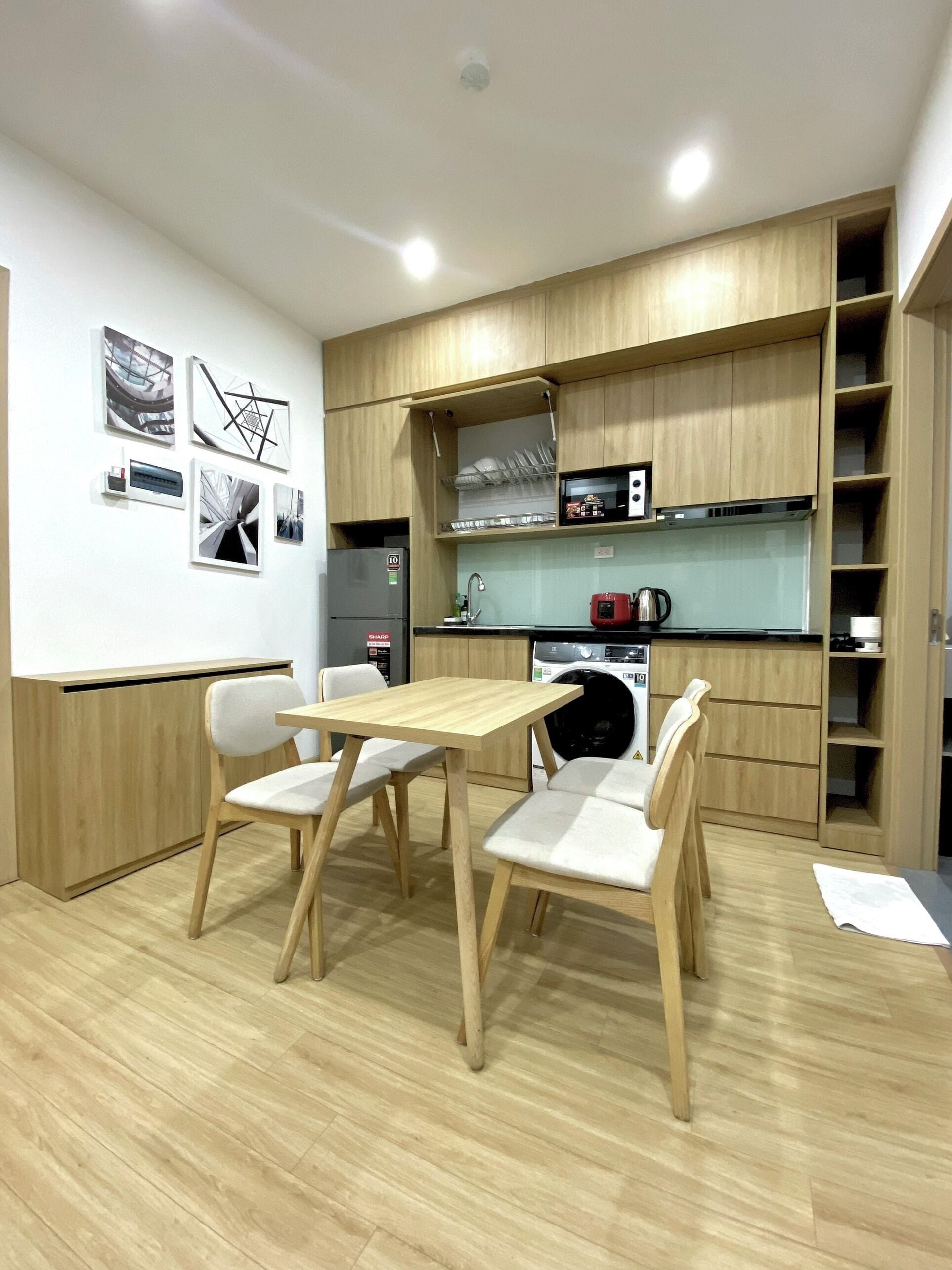 A modern kitchen with wooden cabinets, a dining table with chairs, and a washing machine.