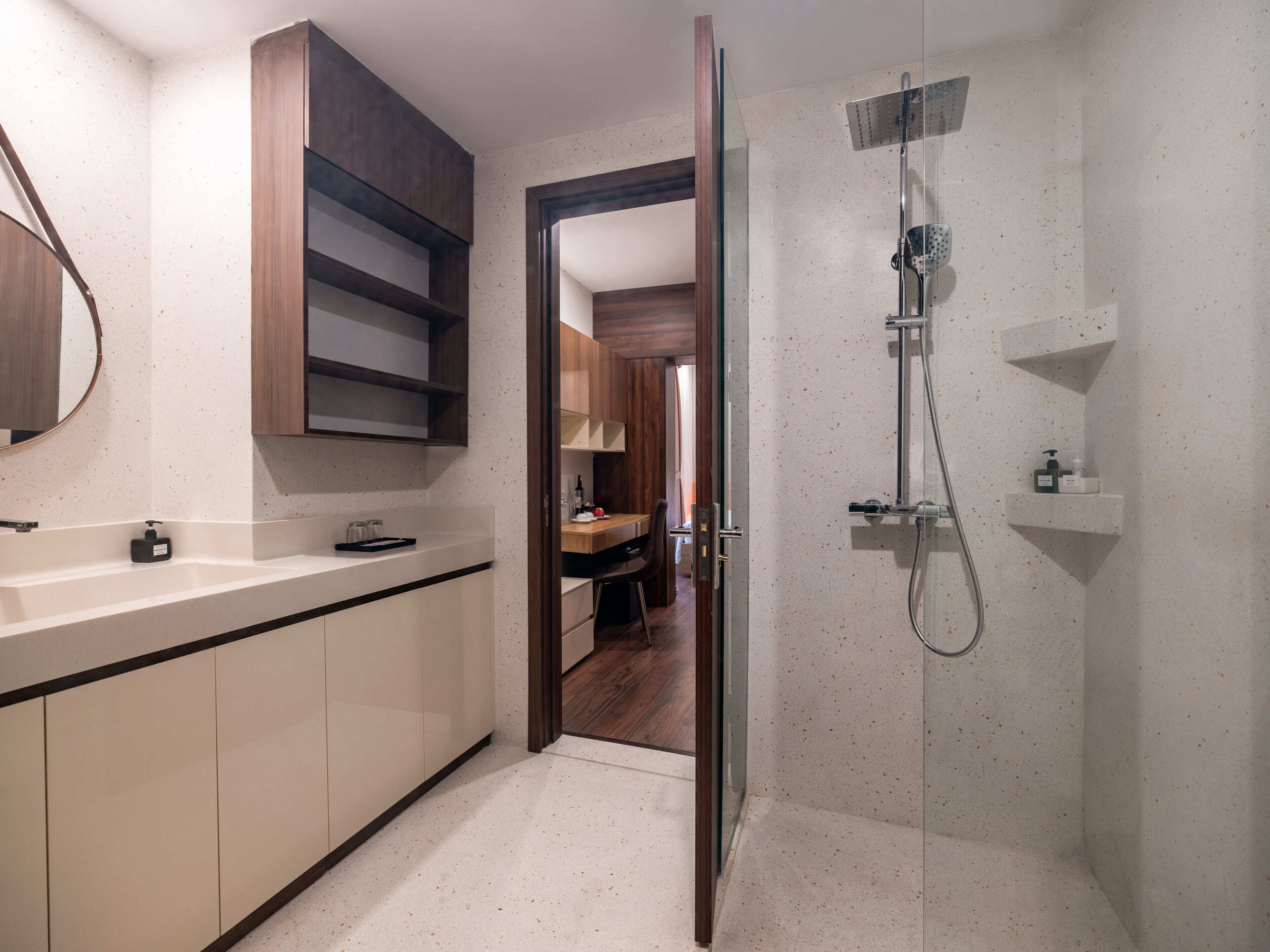 A modern bathroom with a glass shower enclosure, a wooden vanity, and a mirror.