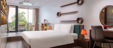 Habitación de hotel moderna con una cama grande, un escritorio con silla, un espejo redondo y vistas al exterior.