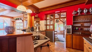 Una cocina con armarios de madera, estufa integrada y una pared de acento roja.