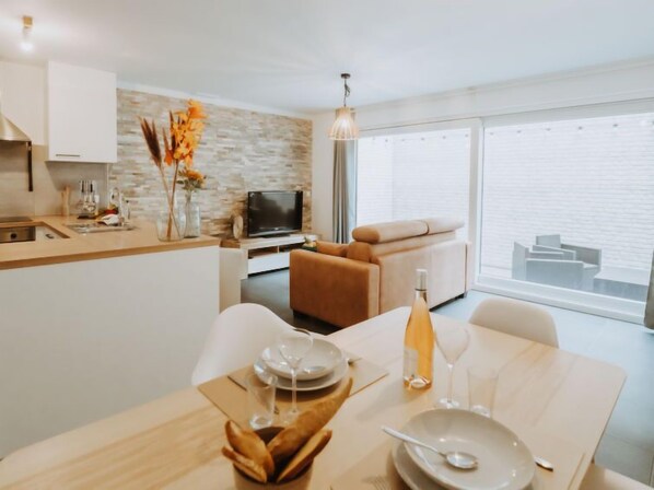 Ein modernes Wohnzimmer mit Essbereich, einer Couch, einem Fernseher und einem Balkon mit Blick.